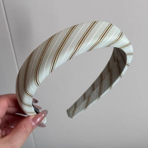 Gros plan d'un serre-tête crème épais avec un motif à rayures marron et blanc