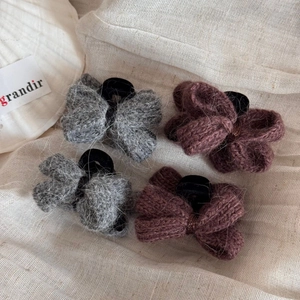 Détail de quatre élastiques à cheveux nœuds tricotés en gris et violet sur tissu de lin