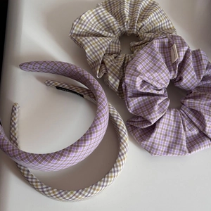 Detailed view of handmade purple, white, and green plaid fabric scrunchies and headbands