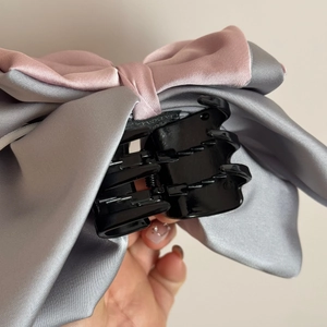 Close-up of pink and grey satin ribbon hair claw clip showing textured fabric and teeth