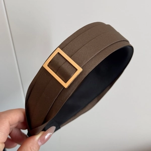 Detail showing deep brown twill fabric texture and polished gold buckle on wide headband