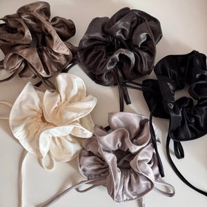 Flat lay of five assorted colors of satin bow scrunchies with elegant silk ribbons