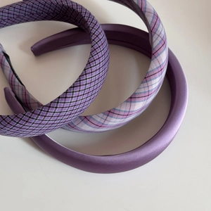 Detailed view of three thick purple fabric headbands in satin and plaid textures