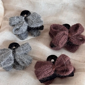 Pinces à cheveux en tricot avec nœuds en gris et café sur fond de tissu beige doux
