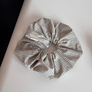 Détail du chouchou à carreaux verts et bleus avec une étiquette blanche Hand Made