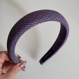 Macro detail of purple checkered fabric headband showing the handmade woven label