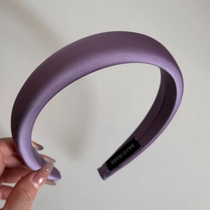 Detail of purple satin headband showing smooth texture and a Hand Made label inside
