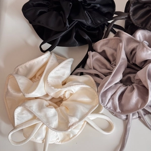 Detailed view of satin hair scrunchies in black, cream white and silver grey silk fabric