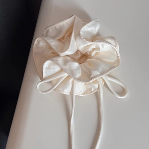 Detailed macro view of the cream white satin scrunchie with layered ruffle texture