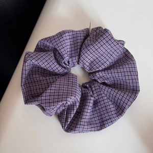 Detailed view of large purple and black checkered fabric scrunchie with soft cotton texture