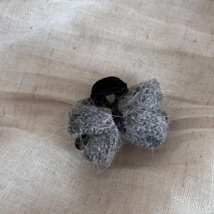 Détail de la pince à cheveux noeud tricoté gris avec texture mohair sur lin beige