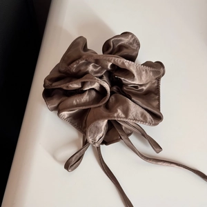 Macro detail of glossy coffee brown satin bow hair tie with silky texture and ribbon