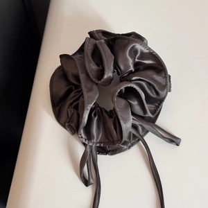 Detail of dark grey satin ribbon scrunchie with silky texture and elegant bow design