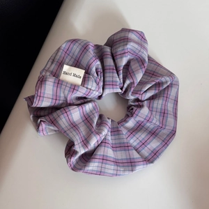 Detailed view of handmade purple and pink checkered fabric scrunchie with woven tag