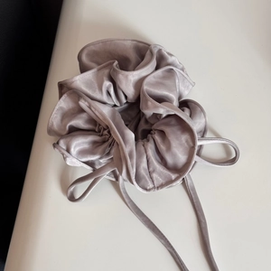 Close-up of champagne satin scrunchie showing silky texture and elegant fabric folds