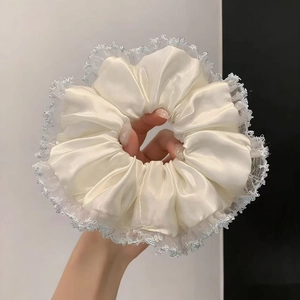 Vue détaillée du chouchou en satin crème avec bordure en dentelle bleu clair