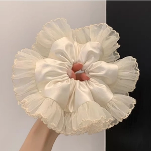 Détail d'un grand chouchou en soie blanche avec bordures en dentelle et texture mesh