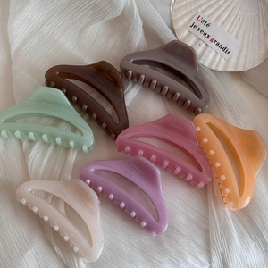 Vue à plat de pinces à cheveux triangulaires évidées aux tons macaron sur tissu blanc
