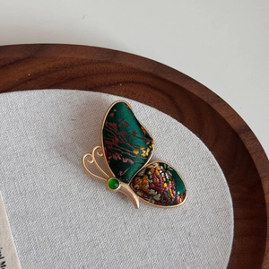 Detail einer Vintage Schmetterling Brosche mit grüner Seidenstickerei und Goldrahmen