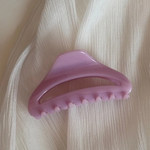 Gros plan d'une pince à cheveux violet clair sur un fond de tissu blanc texturé