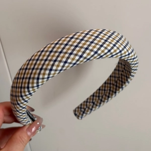 Detailansicht des breiten gepolsterten Stirnbands mit klassischem braun-blauem Karomuster-Stoff
