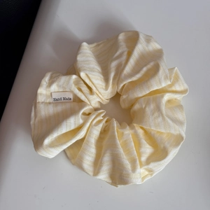 Detail eines gelb gestreiften Scrunchie mit Hand Made Webetikett und weicher Baumwolltextur