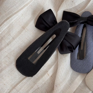 Détail de barrettes à nœuds en satin noir et gris-bleu avec texture en tissu