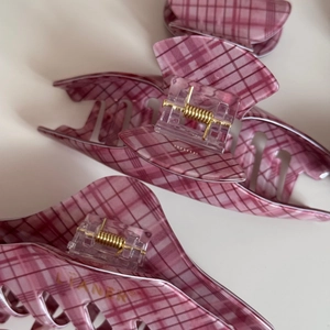 Detail of pink plaid hair claw clip with golden spring and Liane brand engraving