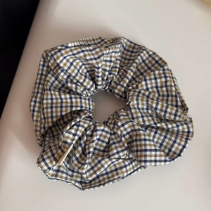 Detailaufnahme des blau-gelb karierten Satin-Haargummis mit feiner Stoffstruktur