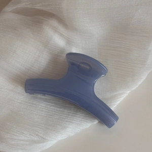 Detailed view of Morandi grey-blue hair claw clip on soft textured white fabric