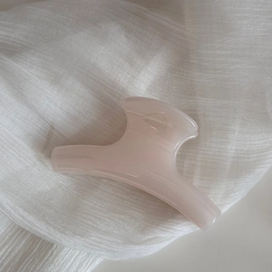 Close-up of a cream pink hair claw clip on white fabric with elegant glossy finish