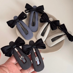 Détail de barrettes à nœuds en tissu élégantes aux tons gris, beige et noir chic