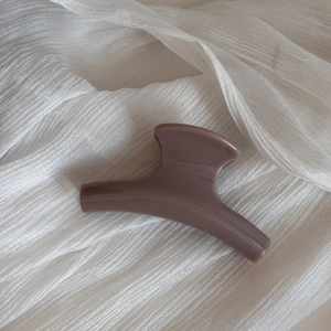 Elegant morandi purple hair claw clip detail on a white textured fabric background