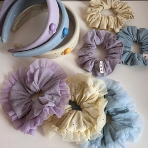 Polka dot lace scrunchies and sponge headbands set in pastel colors on white surface