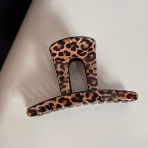 Détail de la pince à cheveux léopard avec finition brillante sur fond gris uni