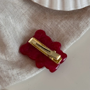 Vista dettagliata del retro di un fermaglio per capelli a orsetto rosso con clip dorata
