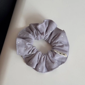 Detailed macro view of purple polka dot lace scrunchie fabric with a white side label