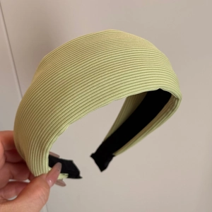 Gros plan d'un bandeau large en tissu côtelé vert clair avec doublure intérieure noire