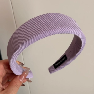Detail shot of purple ribbed fabric headband featuring a black Handmade textile label