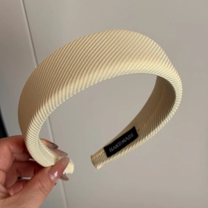 Detail of beige macaron wide sponge headband with diagonal twill fabric texture and handmade label