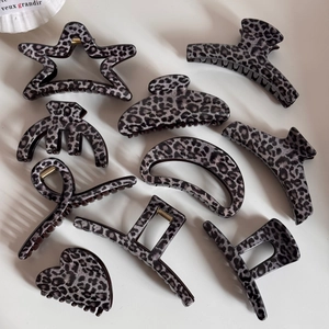 Macro view of a 9-piece set of grey leopard print hair claws in various geometric shapes