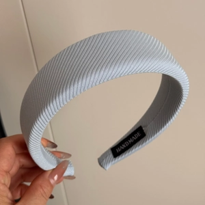 Detailed macro view of light blue ribbed fabric headband with handmade textile label
