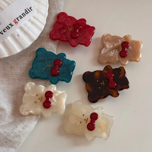 Dettaglio di fermagli per capelli a forma di orsetto in sei colori con fiocchi rossi