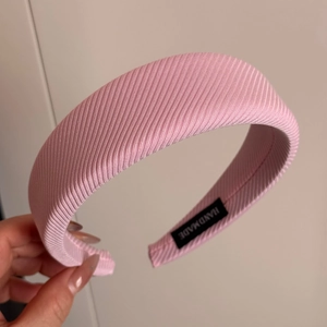 Detailed macro view of pink ribbed fabric headband showing handmade woven label inside
