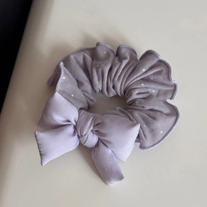 Detailed shot of light purple mesh scrunchie with white polka dots and lace bow