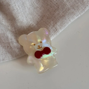 Dettaglio di un fermaglio per capelli a forma di orso bianco con fiocco rosso