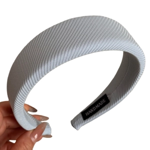 Minimalist wide sponge headband in light blue fabric with handmade label on white background