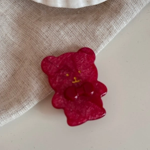 Dettaglio di un grazioso fermaglio per capelli a forma di orso rosso su fondo beige