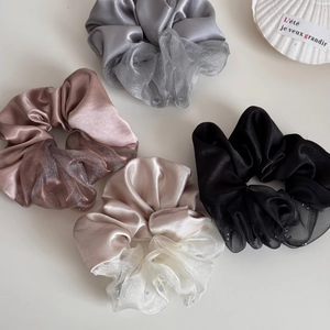 Detailtextuur van satijnen en organza scrunchies in grijs-, roze- en champagnetinten