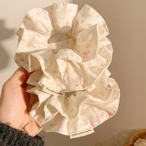 Detailed close-up of handmade floral scrunchies with pink bows and cotton fabric texture